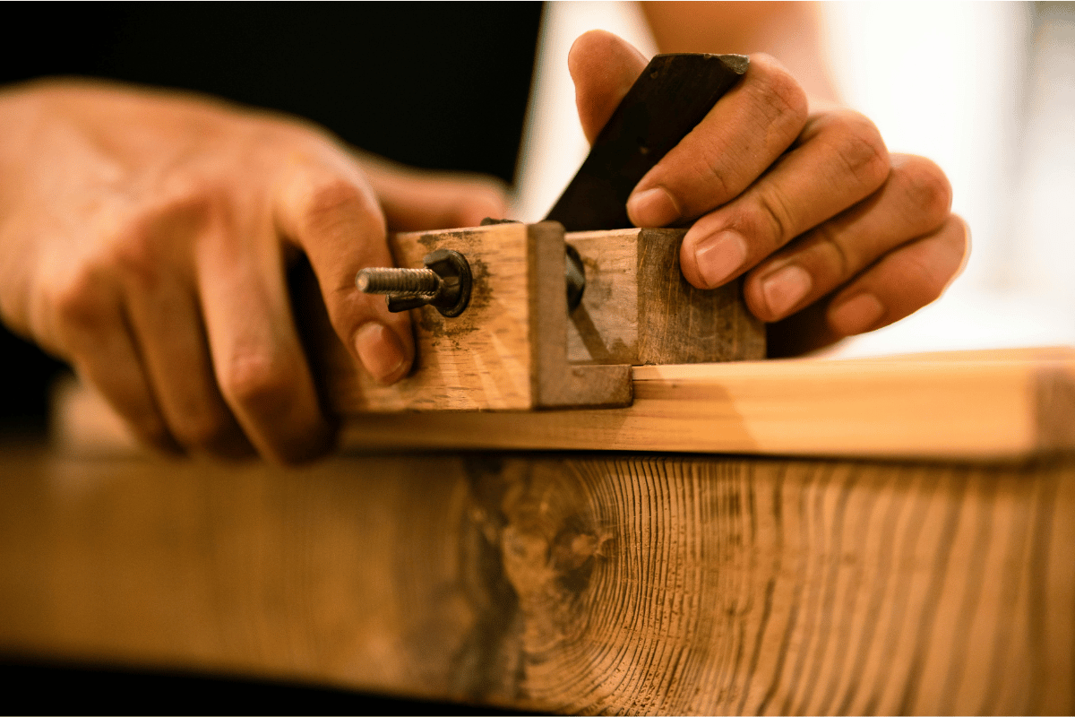 Handwerker bearbeitet Holz mit Hobel